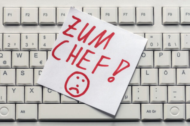 Tastatur mit einem Zettel darauf, auf dem in roter Schrift 'ZUM CHEF!' und ein trauriges Gesicht gezeichnet sind