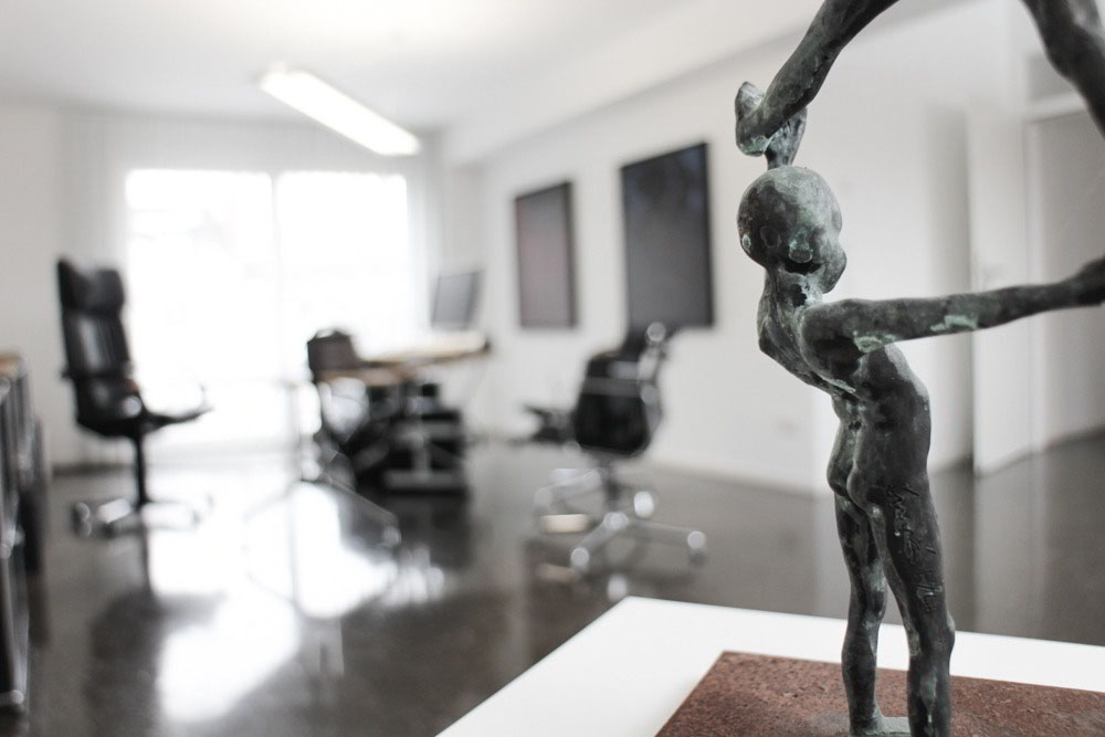 Skulptur einer abstrakten menschlichen Figur in einem modernen Büro mit Stühlen und Tischen im Hintergrund
