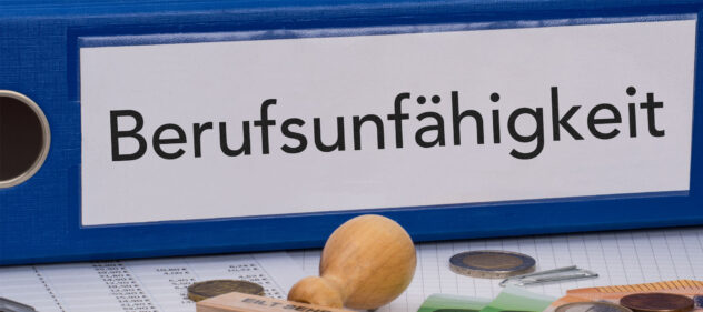 Blauer Ordner mit Aufkleber 'Berufsunfähigkeit' auf einem Schreibtisch mit Stempel, Münzen und Unterlagen