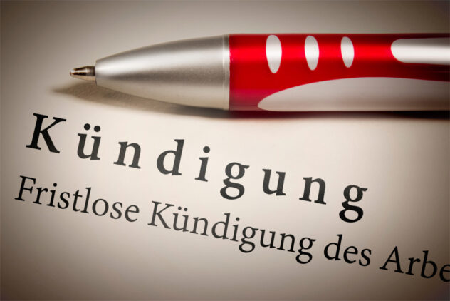 Nahaufnahme eines roten Kugelschreibers auf einem Blatt mit dem Wort 'Kündigung' und dem Text 'Fristlose Kündigung des Arbe'