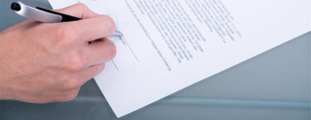 Hand unterschreibt Vertrag mit schwarzem Stift auf weißem Papier